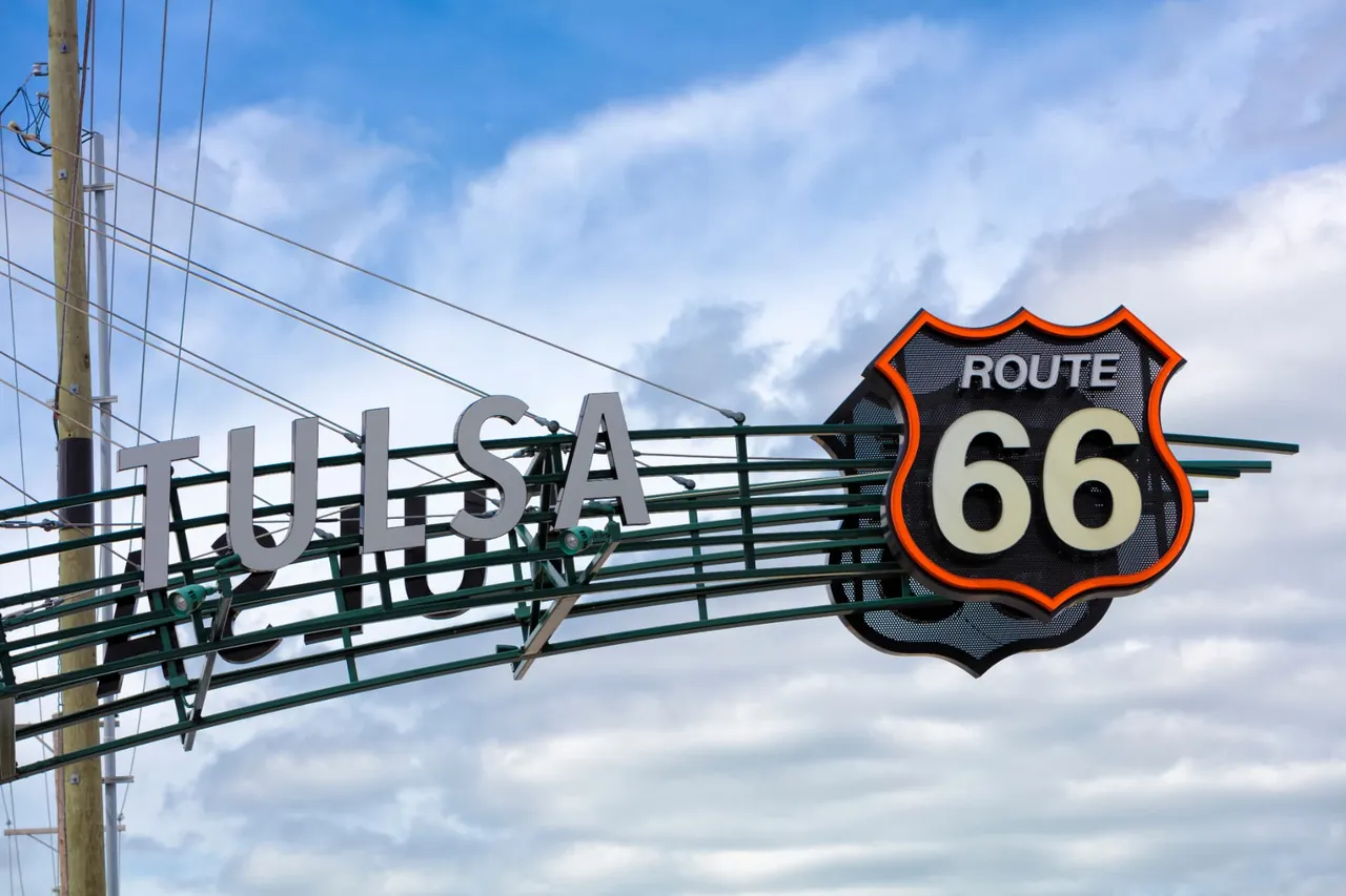The Tulsa Route 66 gateway sign against a cloudy sky.